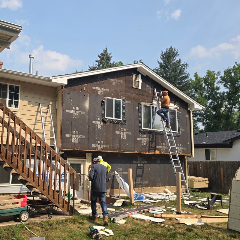 Crew working from ladders along a house wrapped in weather barrier