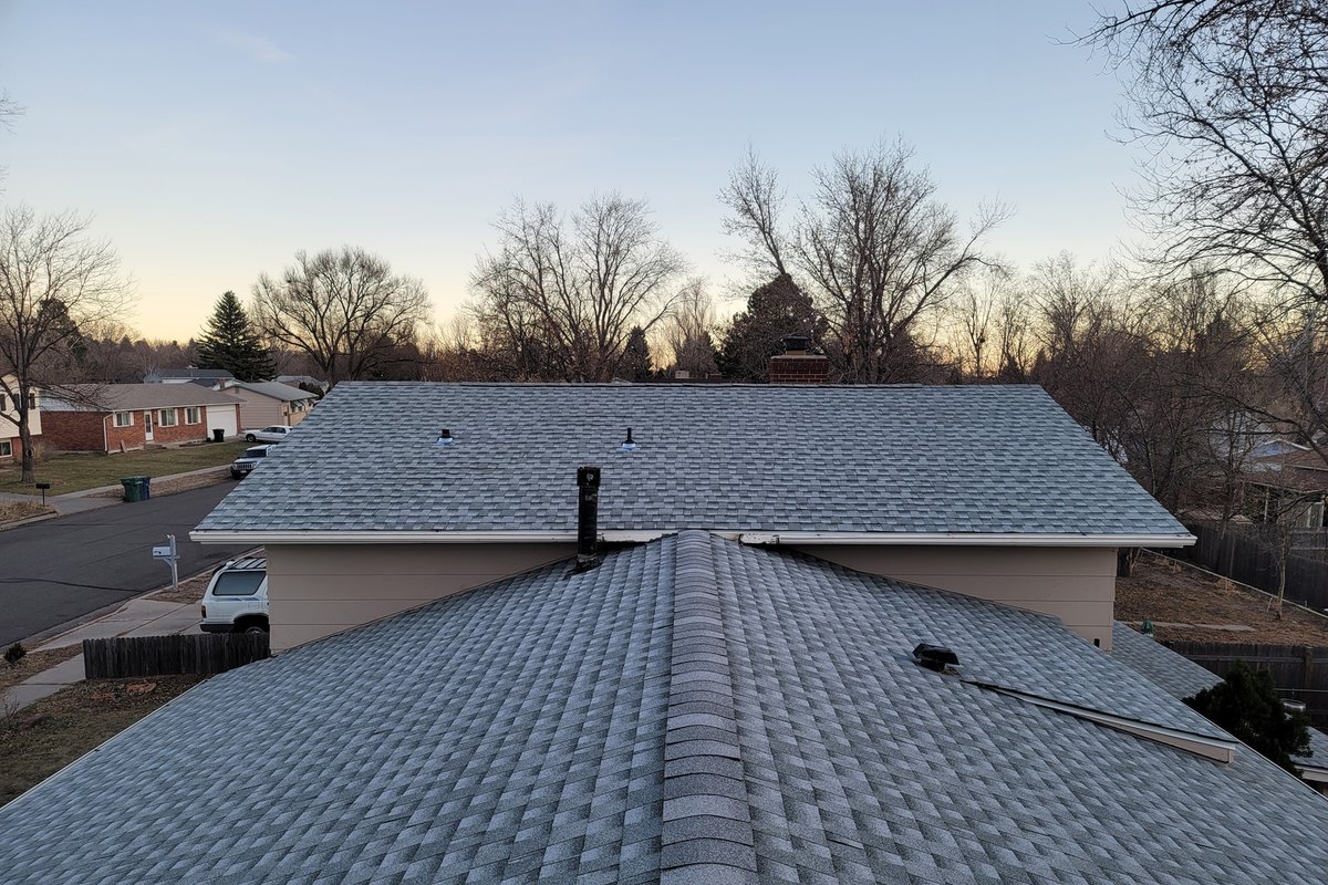 Gray shingle roof plane above a garage on a clear morning