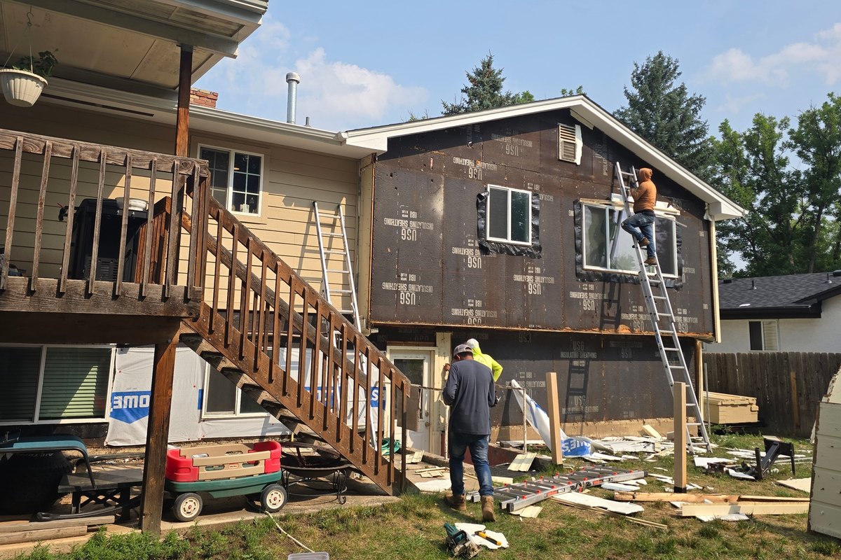 Crew working along a house wrapped in weather barrier before siding