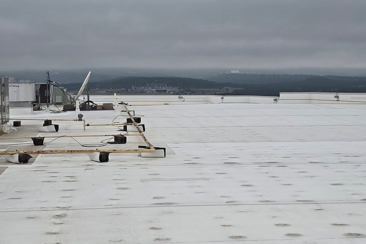 Wide white membrane roof running across the top of a commercial building