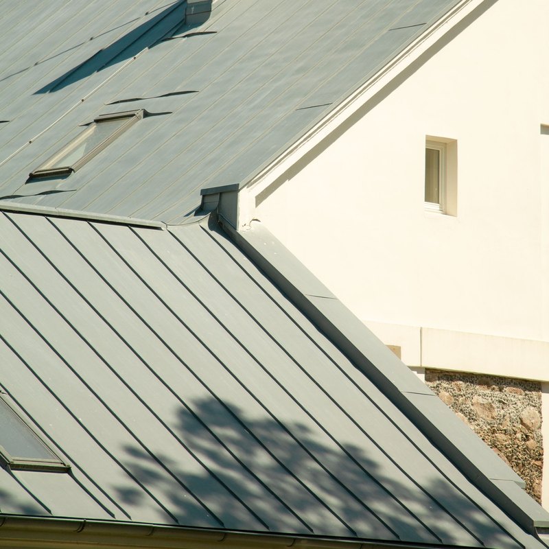 Finished light gray standing-seam metal roof across several residential roof planes
