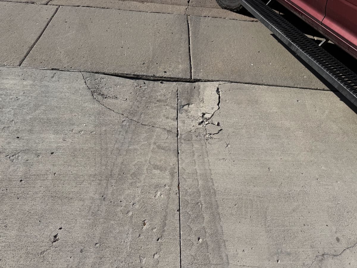 Cracked concrete slab marked by wear near a parked vehicle