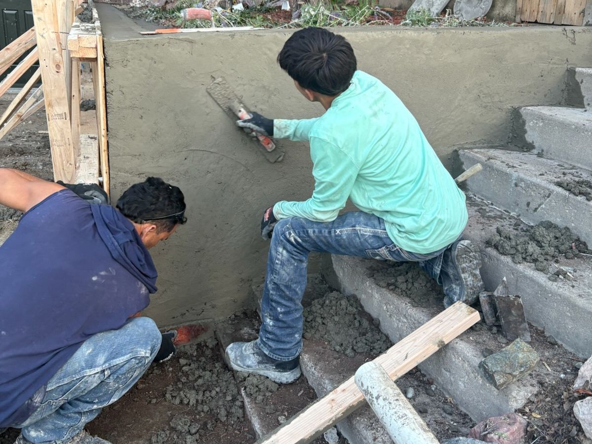 Crew applying a smooth finish to a newly formed concrete retaining wall