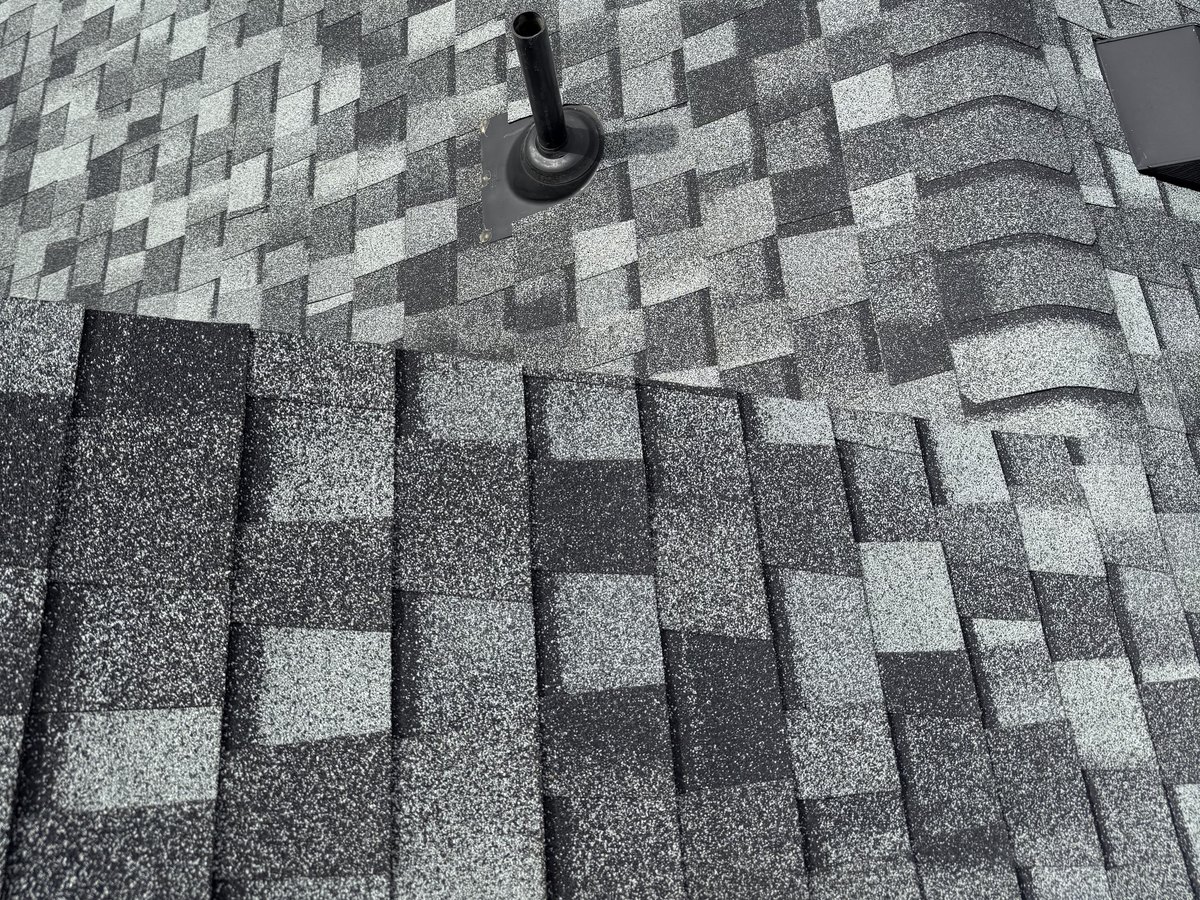 Close view of gray and black architectural shingles around a roof vent
