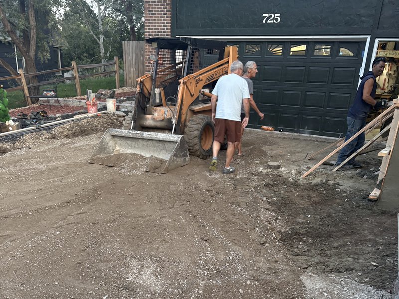 Crew and equipment preparing the ground for a concrete project