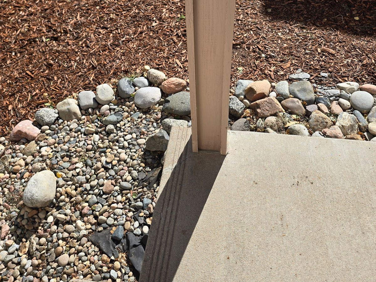 Deck post set into river rock landscaping beside a retaining wall