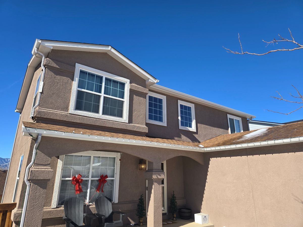 Tan two-story house with a renewed roof above the front entry
