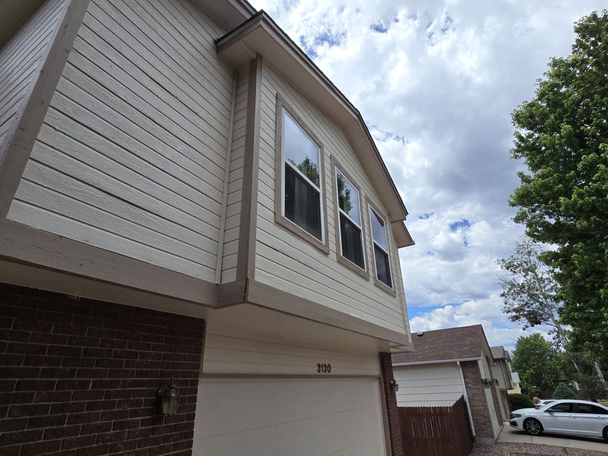 Upward view of house siding, windows, eaves, and part of a garage door