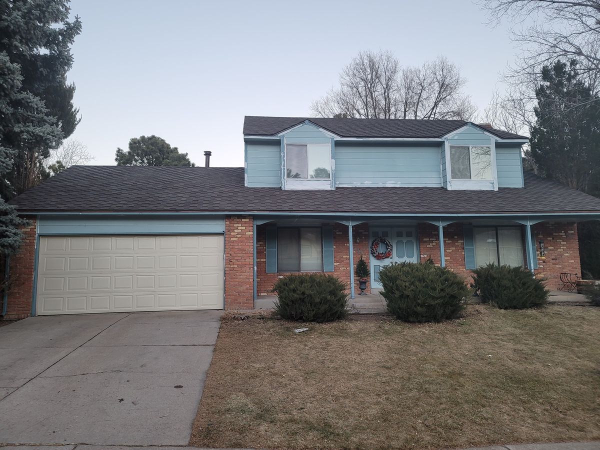 Blue house before exterior painting with trim preparation visible around the windows