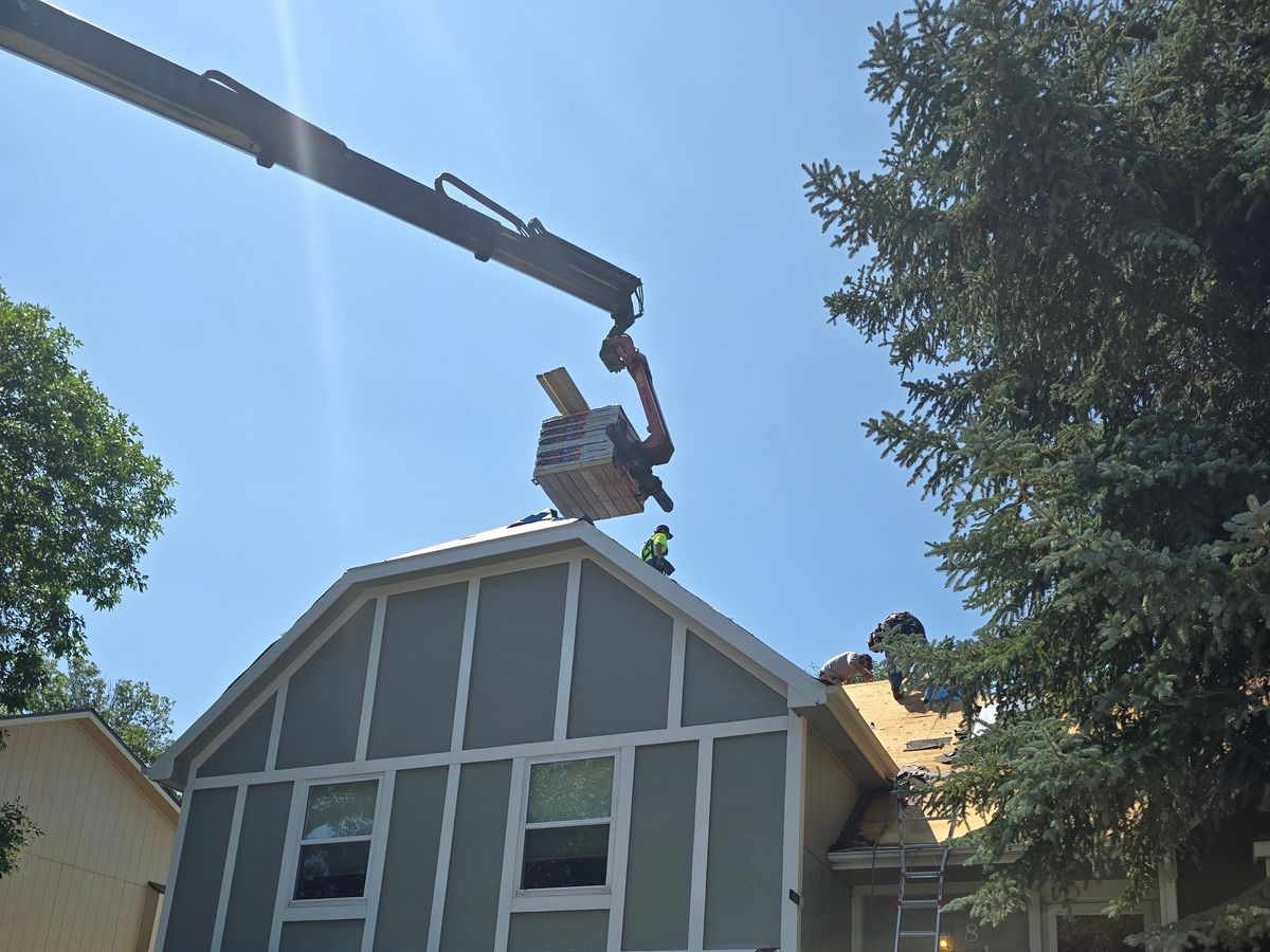 Crane lifting material to a gambrel roof during a siding project