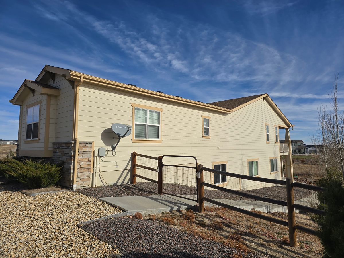 Tan single-story house behind a split-rail fence with its roof renewed