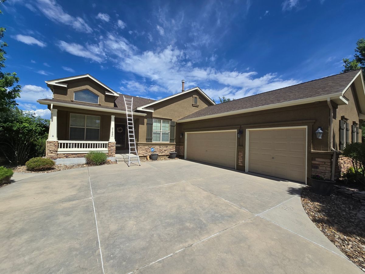 Tan ranch house with a ladder set against the garage roof line
