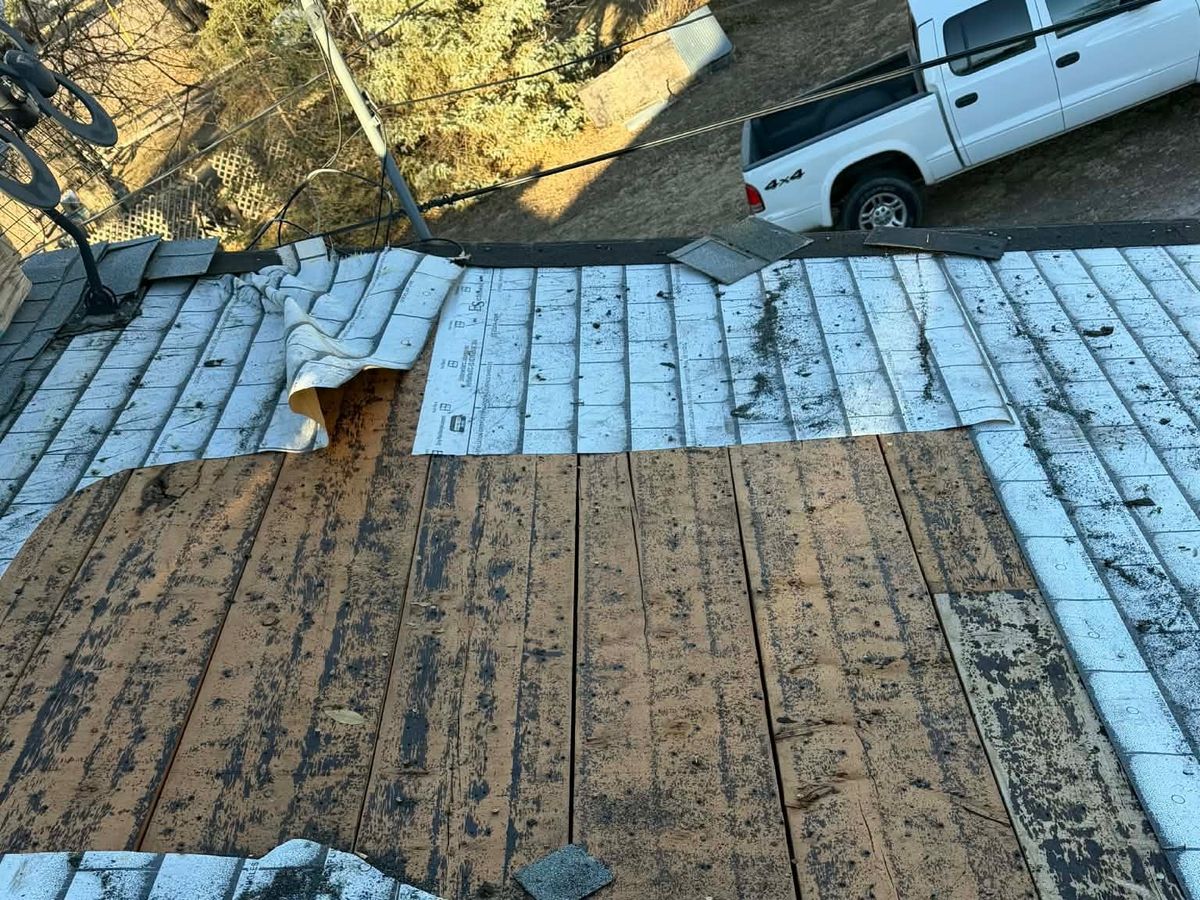 Old shingles coming off beside a run of fresh underlayment