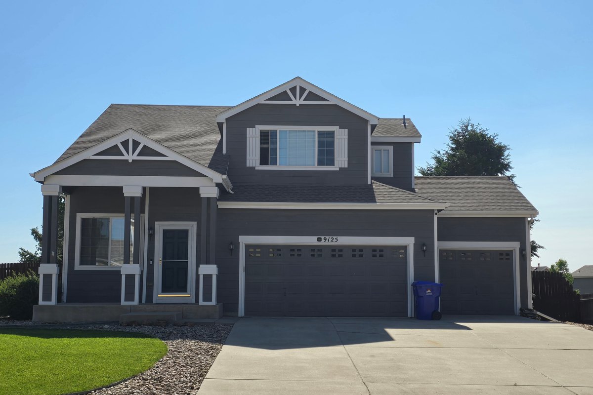 Two-story house with a new gray shingle roof and a three-car garage
