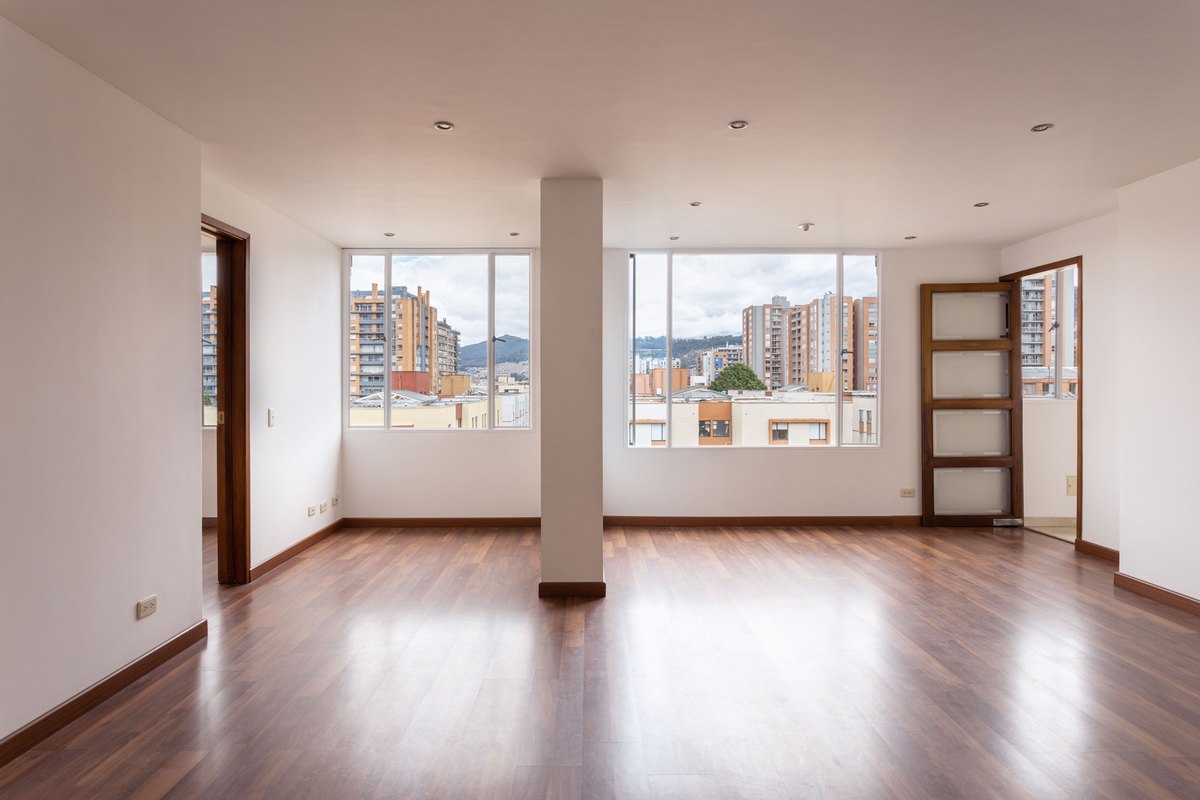 Empty bright room with finished wood flooring and large windows