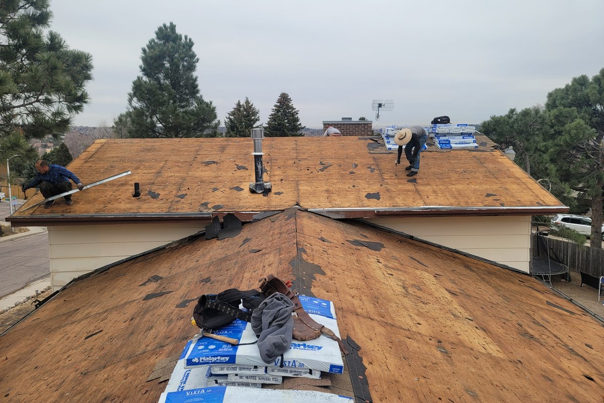 Roofer stripping old shingles from a ridge on a tear-off