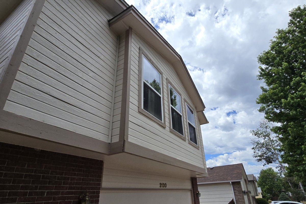 Gutter run along the eave of a tan house beside the garage