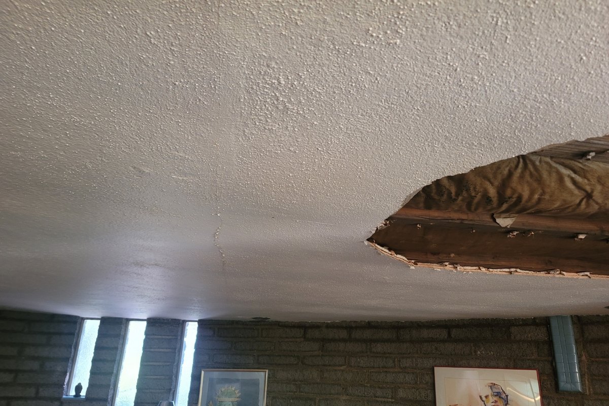 Water-damaged ceiling opened up below a roof leak in a living room