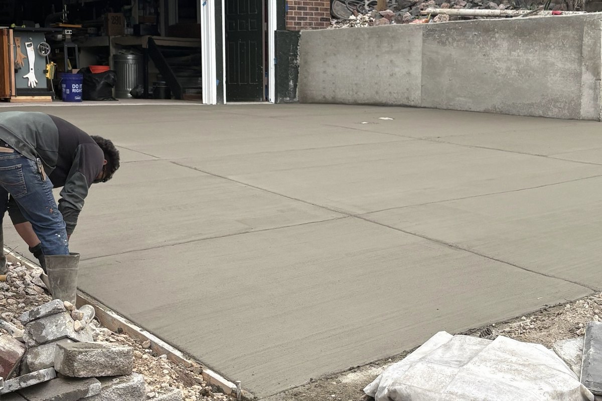 Worker finishing the surface of a freshly poured concrete patio