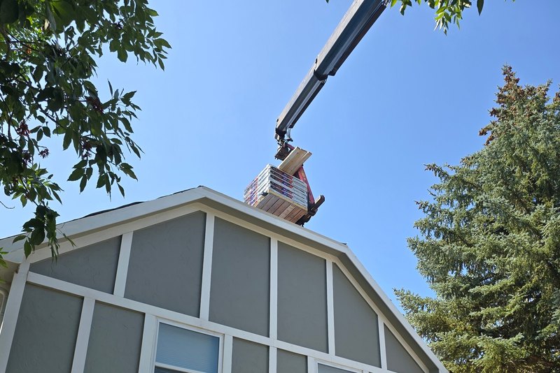 New gray board siding across the gable of a gambrel-roof house