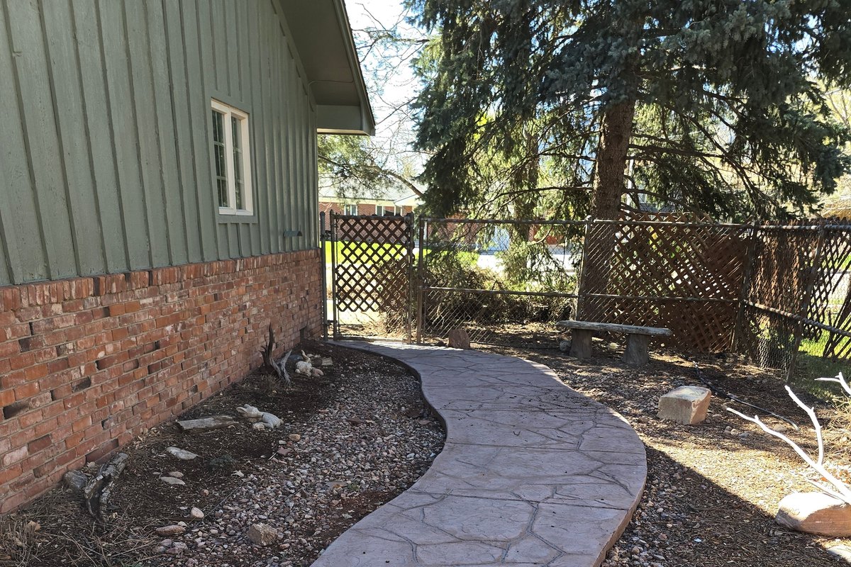 Curved decorative concrete walkway running through a landscaped yard
